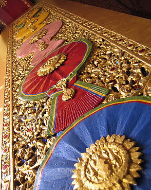 “บานประตูพระวิหาร”  สลักด้วยไม้เป็นลวดลายไทยจำลองรูปดวงตราเครื่องราชอิสริยาภรณ์